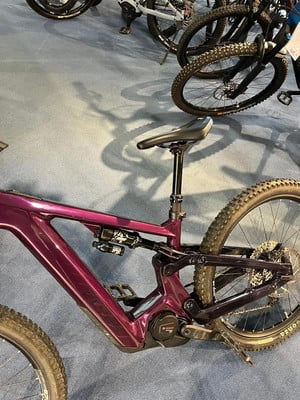 Lila E-Bike mit Federung und BOSCH Antrieb auf blauem Teppich. Lila E-Bike mit Federung und BOSCH Antrieb auf blauem Teppich.