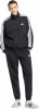 Ein Mann in schwarzer Adidas Trainingskleidung mit weißen Streifen an den Ärmeln und Logo.