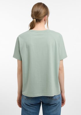 Rückansicht einer Frau in einem grünen T-Shirt und Jeans.