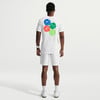 Ein Mann im weißen T-Shirt mit Tennisball-Aufdruck und weißer Shorts.