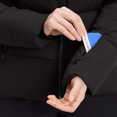 Frau steckt eine Karte in eine Ärmeltasche einer schwarzen Jacke. Frau steckt eine Karte in eine Ärmeltasche einer schwarzen Jacke.
