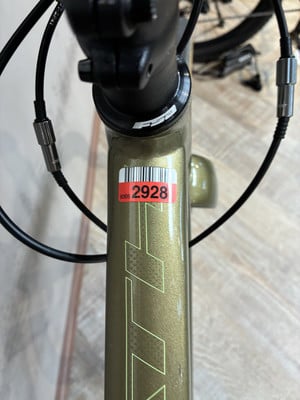 Goldener Fahrradrahmen mit einem roten Aufkleber mit Barcode und der Nummer 2928. Goldener Fahrradrahmen mit einem roten Aufkleber mit Barcode und der Nummer 2928.