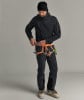 Mann in schwarzer Kleidung und Gurtzeug schließt Karabiner.