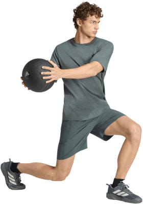Ein Mann in grauer Kleidung macht eine Übung mit einem Medizinball. Ein Mann in grauer Kleidung macht eine Übung mit einem Medizinball.