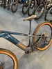 Ein blaues Trek E-Bike mit orangefarbenen Felgen auf blauem Teppich.