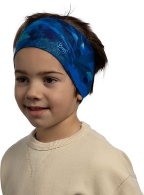 Ein Junge mit blauem bedrucktem Stirnband und beigem Pullover lächelt. Ein Junge mit blauem bedrucktem Stirnband und beigem Pullover lächelt.