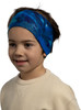 Ein Junge mit blauem bedrucktem Stirnband und beigem Pullover lächelt.
