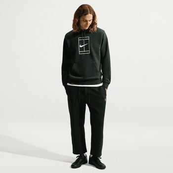 Ein Mann in einem schwarzen Nike Hoodie und Hose steht vor weißem Hintergrund.