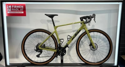 Ein grünes KTM Gravelbike mit braunen Reifen auf einem Ständer.