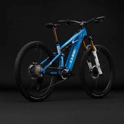 Ein blaues Cube E-Bike mit Federung und schwarzen Rädern vor dunklem Hintergrund.