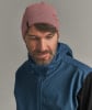 Ein Mann mit einer rosa Mütze und einer blauen Jacke blickt nach unten.