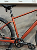 Orange Mountainbike mit schwarzem Sattel und Kettenantrieb.
