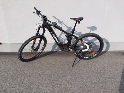 Ein schwarzes Haibike E-Mountainbike steht vor einer grauen Wand auf Asphalt. Ein schwarzes Haibike E-Mountainbike steht vor einer grauen Wand auf Asphalt.