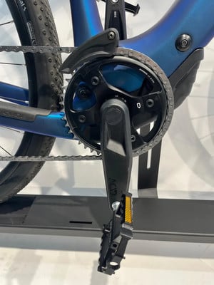 Detail des Kettenblatts und Pedals eines blauen E-Bikes mit Kette. Detail des Kettenblatts und Pedals eines blauen E-Bikes mit Kette.