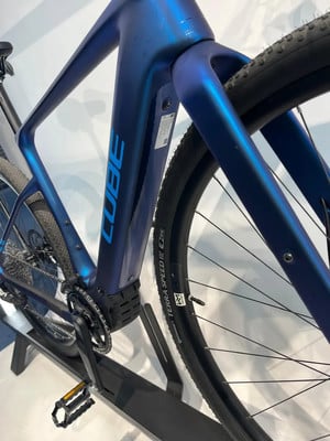 Detail eines blauen E-Bikes mit CUBE-Logo und Geländereifen. Detail eines blauen E-Bikes mit CUBE-Logo und Geländereifen.